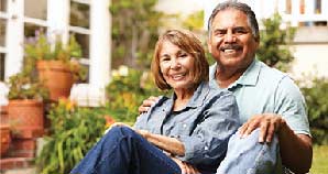 Couple sitting in their yard smiling.